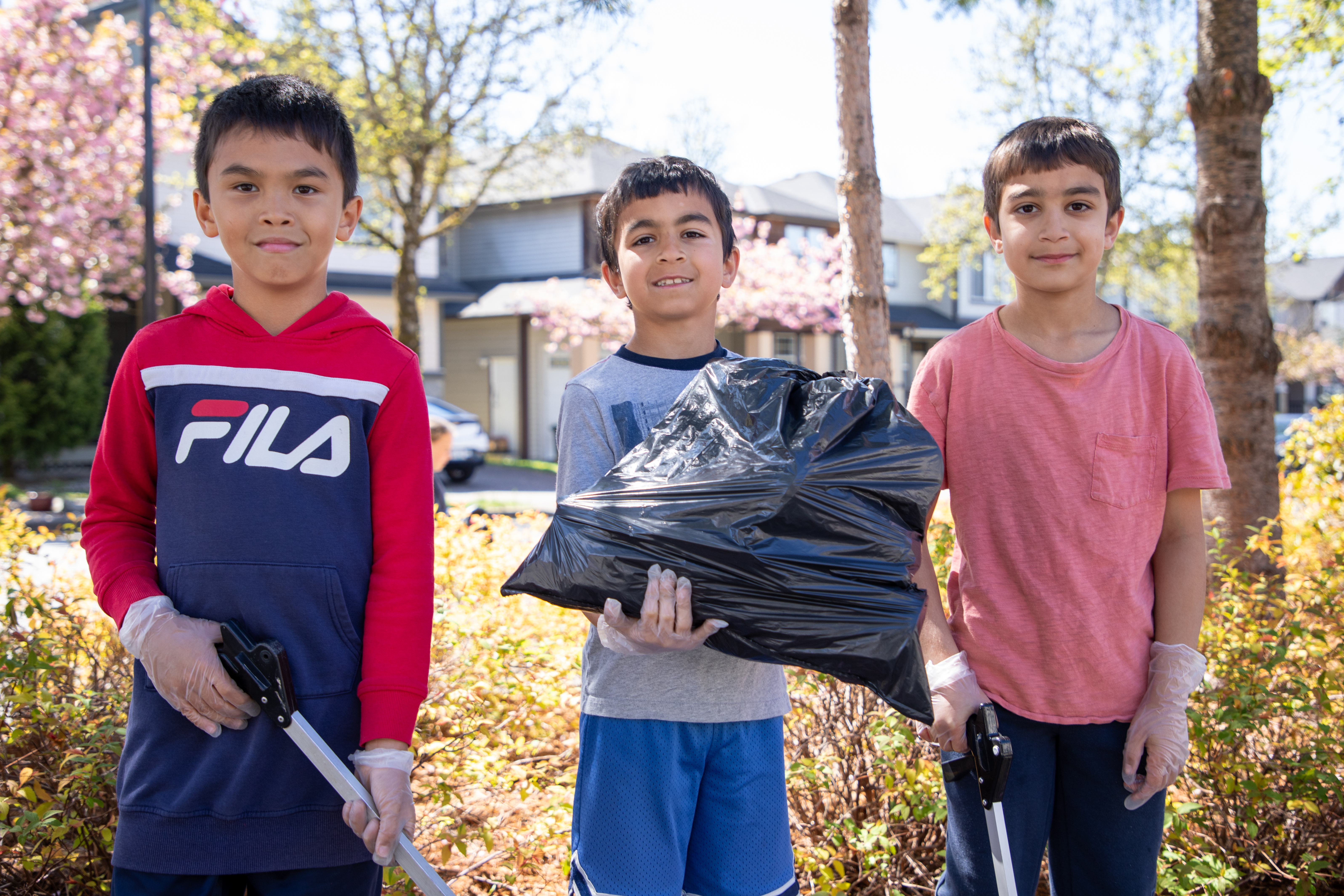 Albion Elementary students hold up full garbage bag after their community cleanup.
