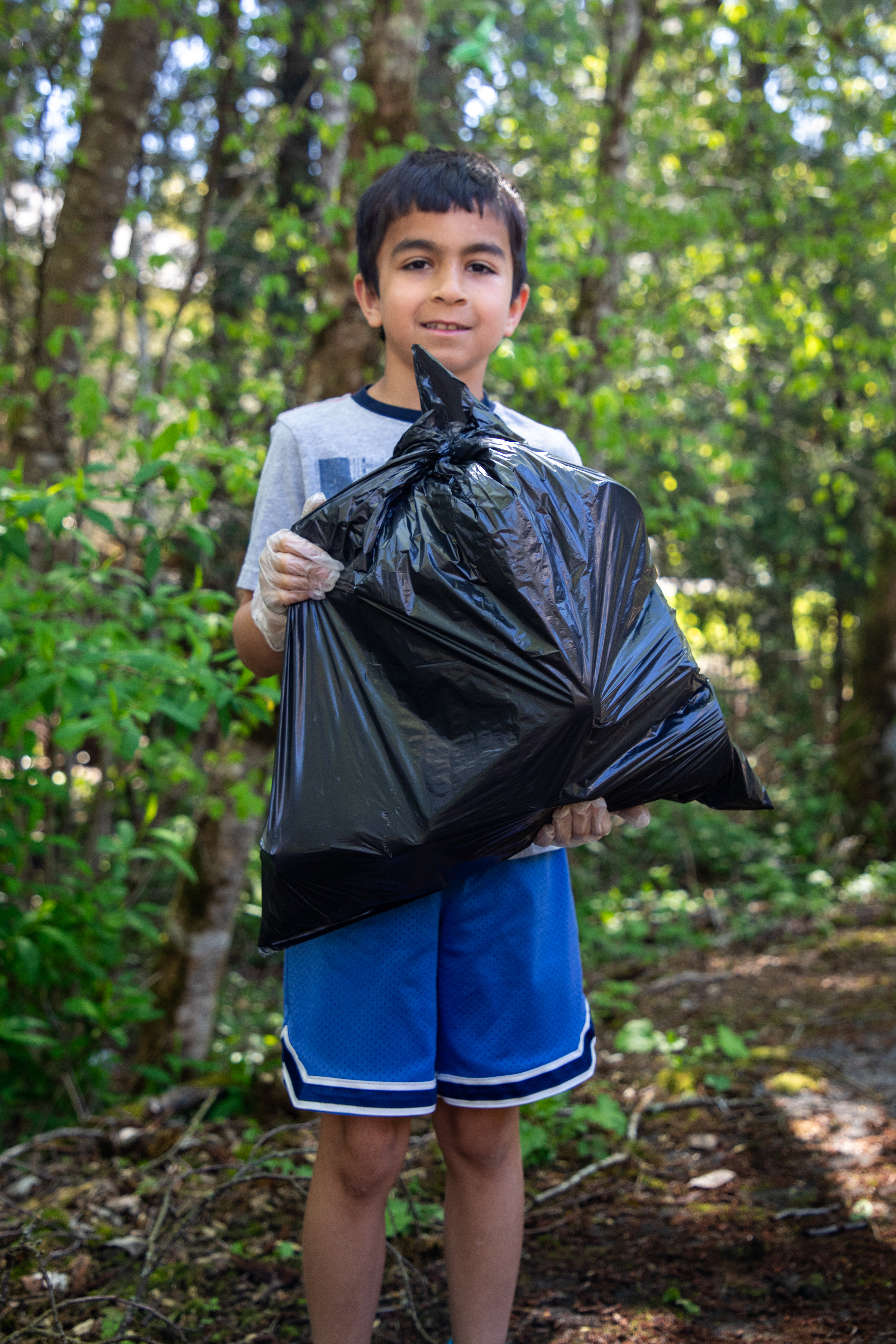 Albion Elementary student holding up full garbage bag after community cleanup.